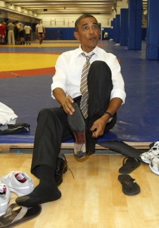 U.S. President Obama puts his shoes back on after meeting wrestlers on the mat as he visits the U.S. Olympic Training Facility in Colorado Springs